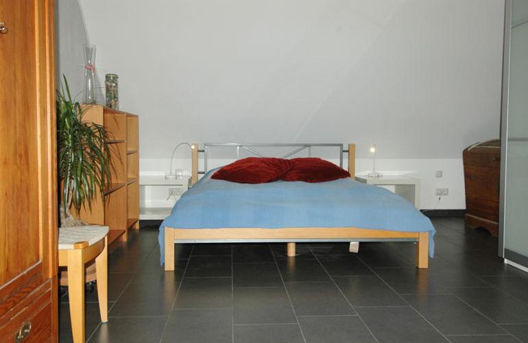 a bedroom with a bed with a red and blue blanket at Ole & Trude in Kiel