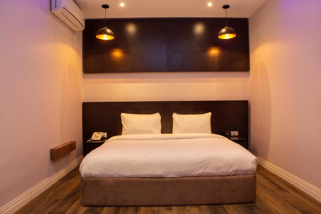 - une chambre avec un grand lit et deux lampes dans l'établissement Riivana Tavern, à Lekki