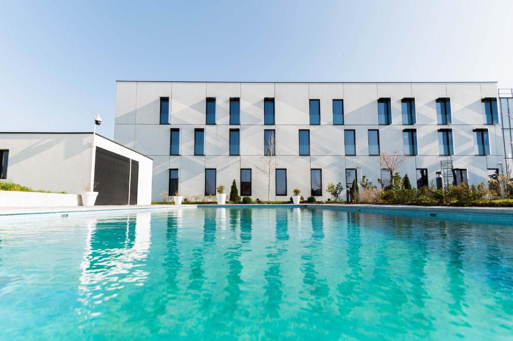 a swimming pool in front of a building at Hôtel Dali Val d'Europe in Chanteloup-en-Brie