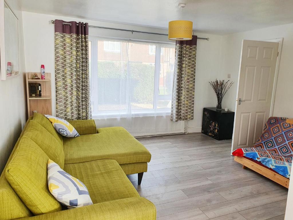 a living room with a yellow couch and a window at Rabbit Haven - 4 minutes from Bicester Village! in Bicester
