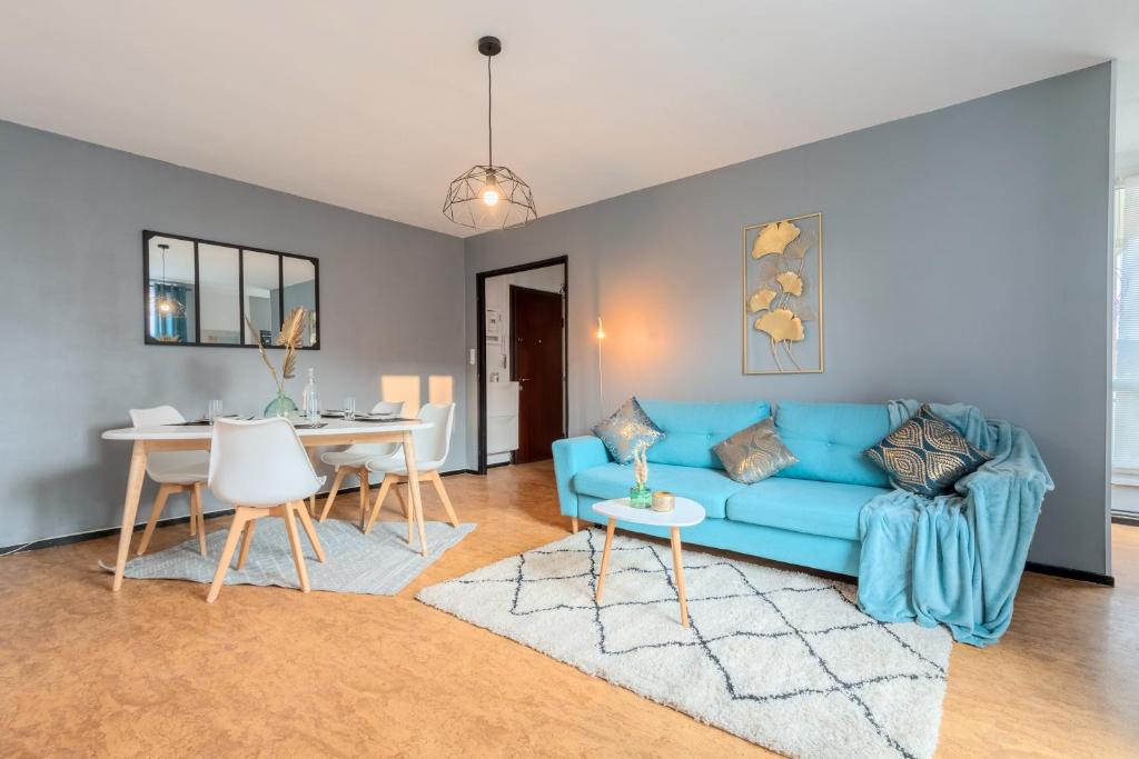 a living room with a blue couch and a table at Grand T2 à 8mn de Lille et Stadium Terrasse et parking privé in Villeneuve d'Ascq