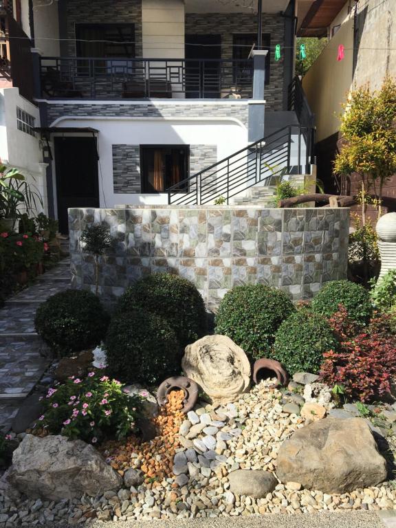 um jardim em frente a uma casa com pedras e plantas em La Famille em Baguio