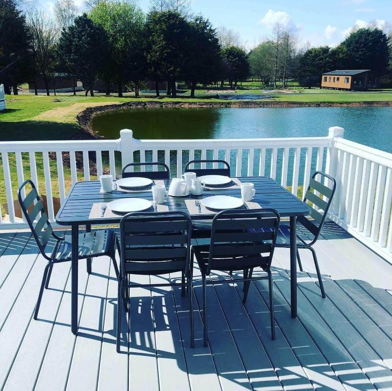 une table et des chaises bleues sur une terrasse à côté de l'eau dans l'établissement Hemingway Lodge with Hot Tub, à York