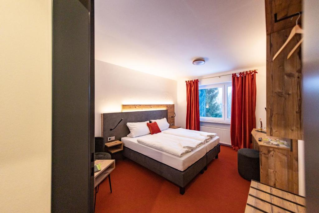um quarto de hotel com uma cama e cortinas vermelhas em Am Ochsenkopf em Bischofsgrün
