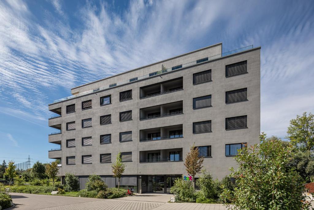 duży betonowy budynek z niebieskim niebem w obiekcie Aparthotel-aarau-WEST Swiss Quality w mieście Oberentfelden