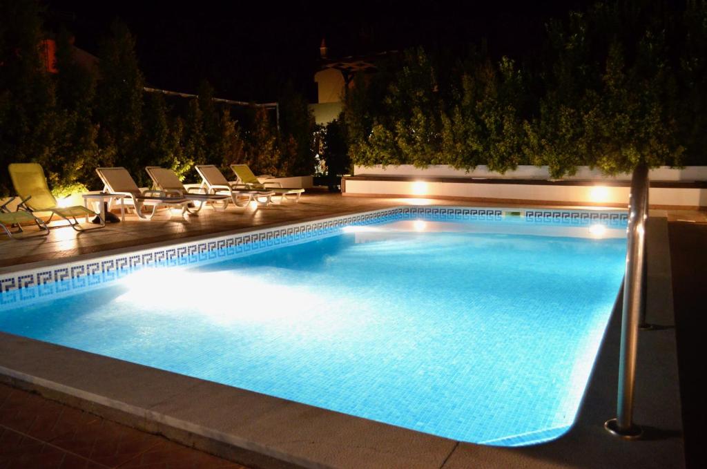 a swimming pool at night with chairs and lights at Villa ELTAEL - Rita Apartment - Piscina Aquecida e Partilhada in Manta Rota