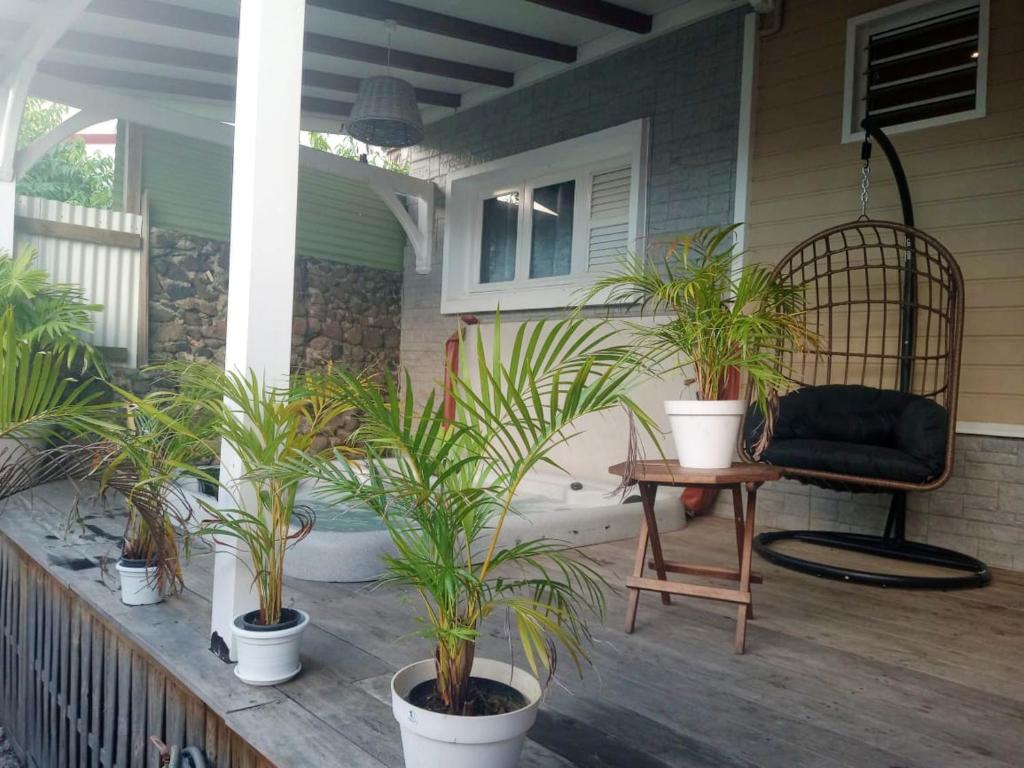 a porch with potted plants and a chair at Appartement d'une chambre avec vue sur la ville jacuzzi et jardin clos a Le Vauclin a 2 km de la plage in Le Vauclin