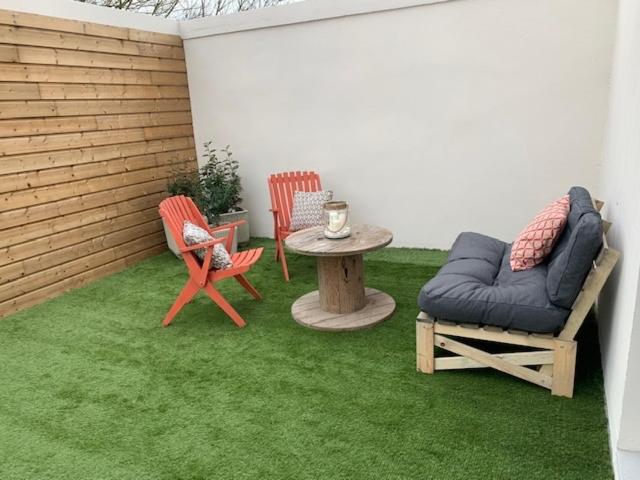 eine Terrasse mit 2 Stühlen, einem Tisch und einem Sofa in der Unterkunft LES JARDINS avec terrasse in Amiens