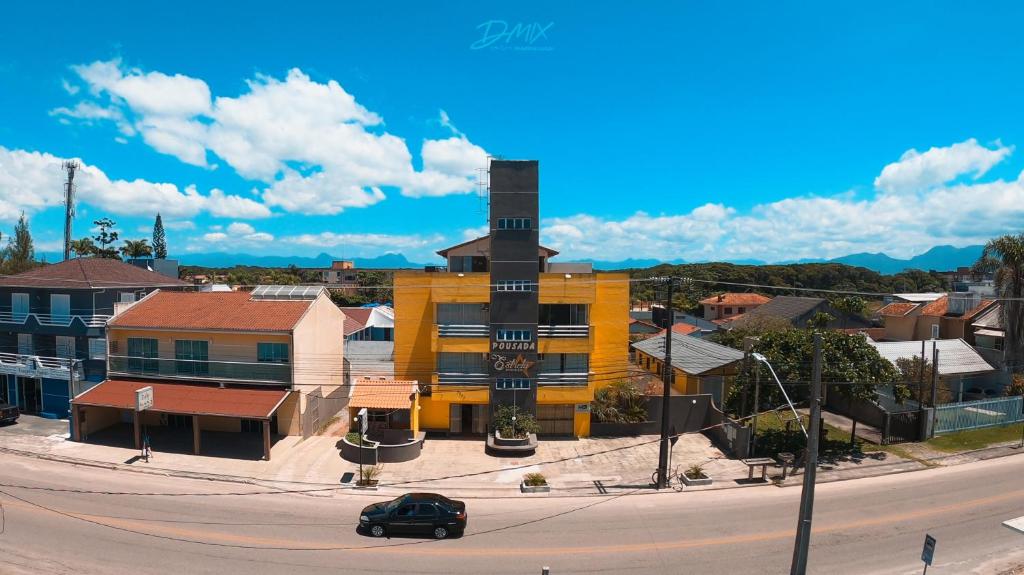 un edificio giallo con una torre dell'orologio su una strada cittadina di Pousada Estrela Dourada a Guaratuba
