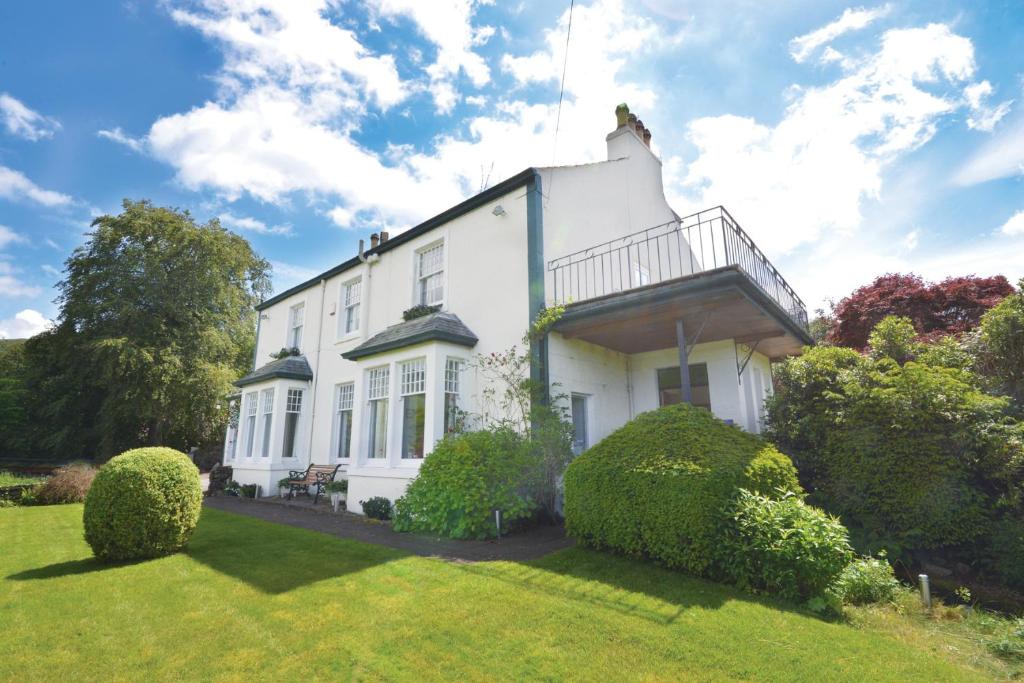 a white house with a balcony on a lawn at Skiddaw Grove in Keswick