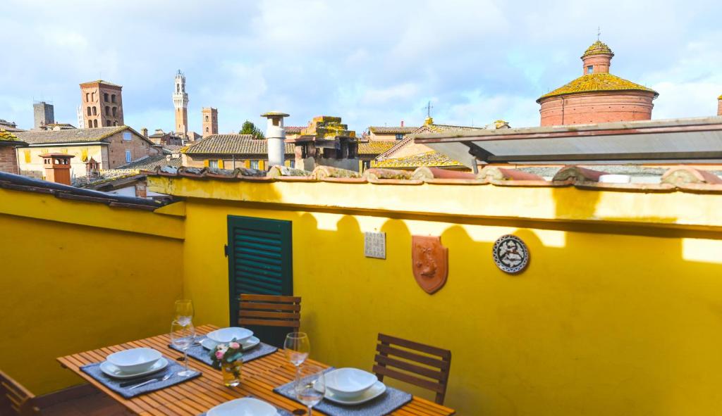 une maison jaune avec une table et des plaques dans l'établissement Un terrazzo sulla magia, à Sienne