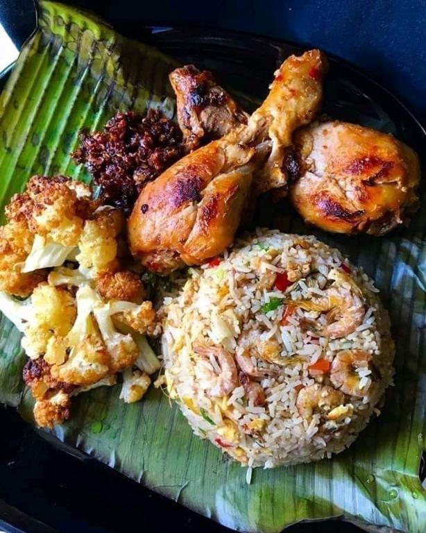 a plate of food with chicken and rice on a banana leaf at Goyambokka Guesthouse in Tangalle