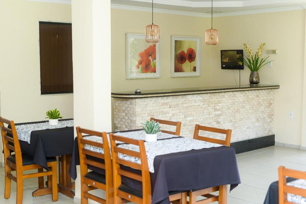 una sala da pranzo con due tavoli e sedie con piante di Hotel Luma a Itaguaí