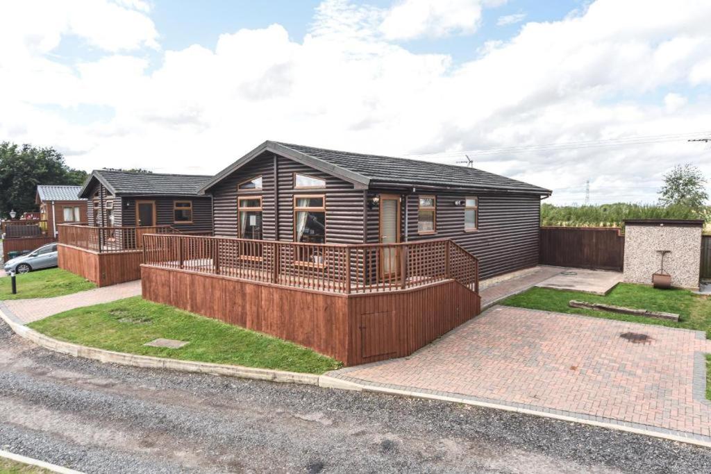a house with a large deck on a driveway at #2 Delightful 3 bedroom holiday lodge no hot tub 