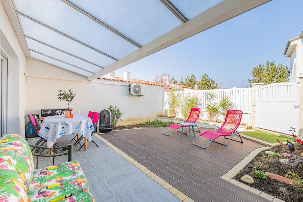 un patio con sillas rosas y una mesa en Villa moderne et coloree a Jard sur mer, en Jard-sur-Mer