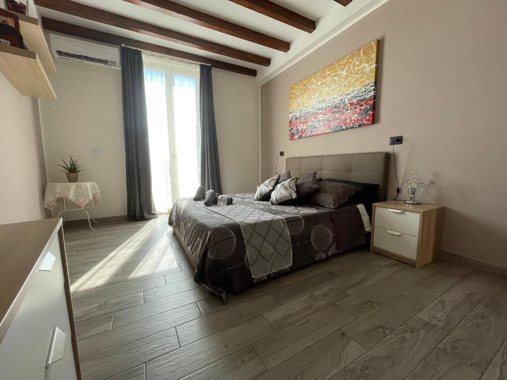 1 dormitorio con 1 cama y una pintura en la pared en Luxury Home Keops en Catania