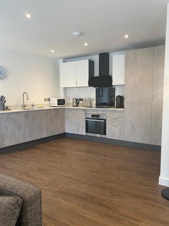 a large kitchen with white cabinets and a wooden floor at Icona - Stylish 2 bed apartment in York