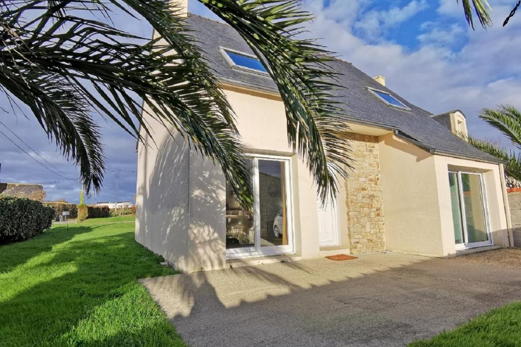 a house with a palm tree in front of it at Maison Bretagne bord de mer in Guissény