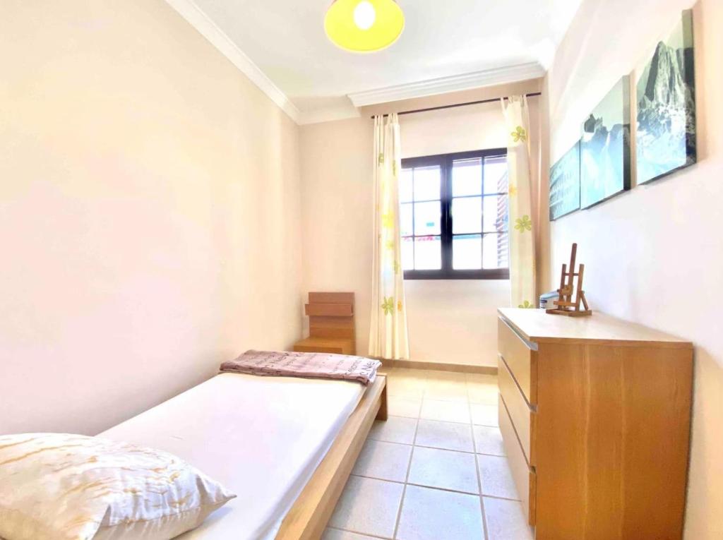 ein Schlafzimmer mit einem Bett, einer Kommode und einem Fenster in der Unterkunft Villa Ágatha, vacaciones en familia en Lanzarote in Playa Blanca