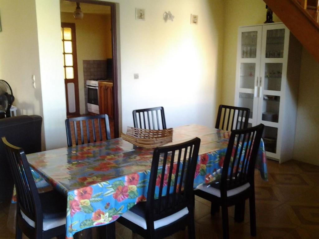 a dining room table with four chairs and a table cloth at MAISON de VACANCES ANSES D'ARLET in Les Anses-dʼArlets