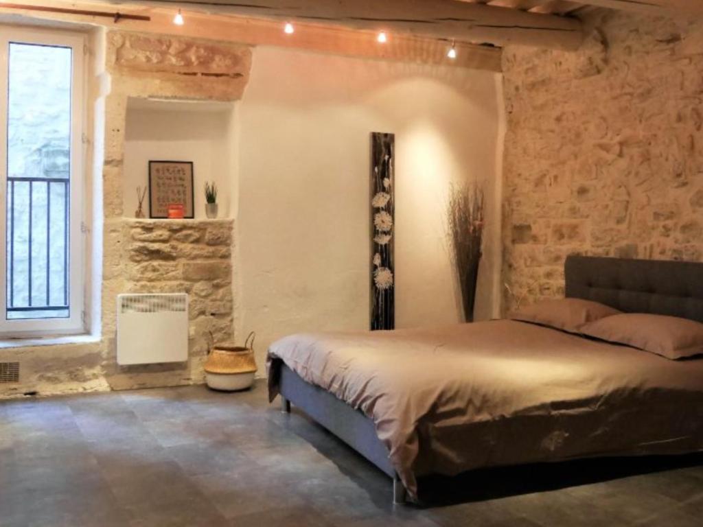 ein Schlafzimmer mit einem Bett und einer Steinmauer in der Unterkunft L'Etoile in Nîmes