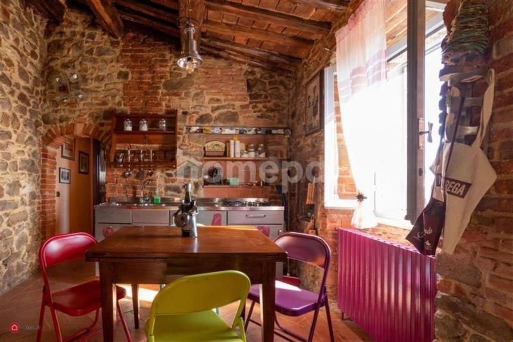 a kitchen with a wooden table and colorful chairs at NIDO SCANSANESE in Scansano