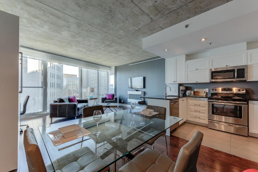 cocina y sala de estar con mesa de cristal y sillas en Les Immeubles Charlevoix - Le 760310 en Quebec