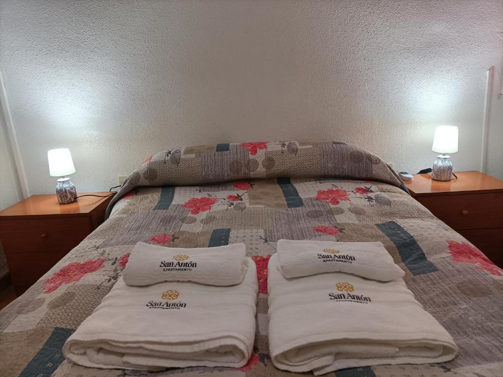 a bed with three towels on it with two lamps at Apartamentos San Antón 2 in Córdoba
