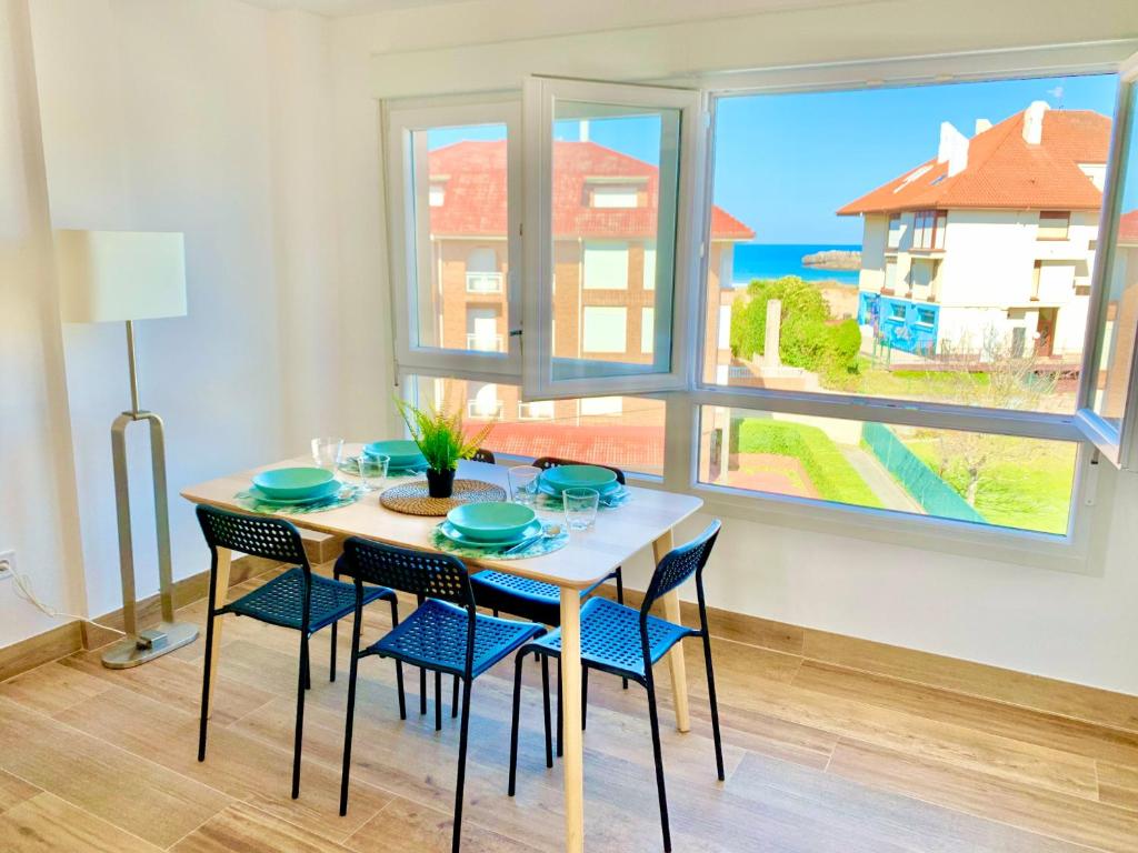 a dining room with a table and chairs and a window at Apartamento Arenal ATICO in Noja