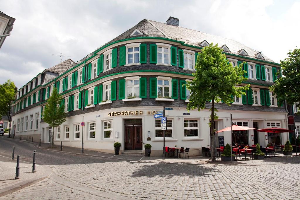 ein großes, grün-weißes Gebäude auf einer Straße in der Unterkunft Hotel Gräfrather Hof in Solingen