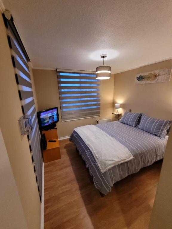 ein Schlafzimmer mit einem Bett und einem TV in der Unterkunft San Pedro de la Paz by Luxury Apartment Chile in San Pedro de la Paz