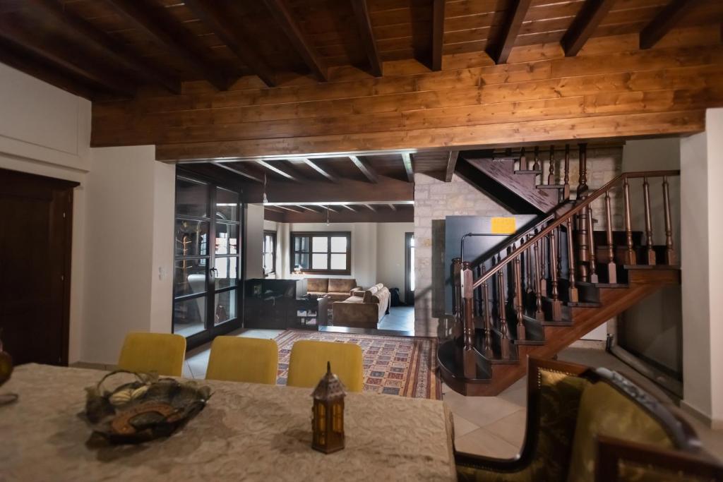 ein Wohnzimmer mit einem Esstisch und einer Treppe in der Unterkunft Kourtis Family Mansion in Karpenisi