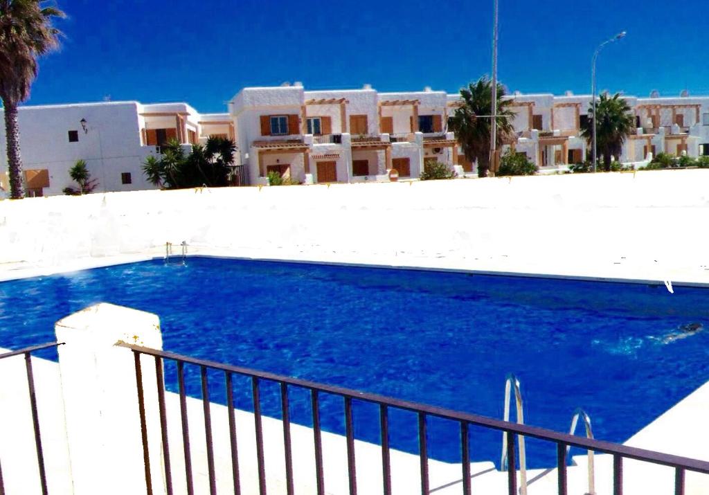 une grande piscine bleue en face d'un bâtiment dans l'établissement Urb Las Cañas Apartamento B3, à Tarifa