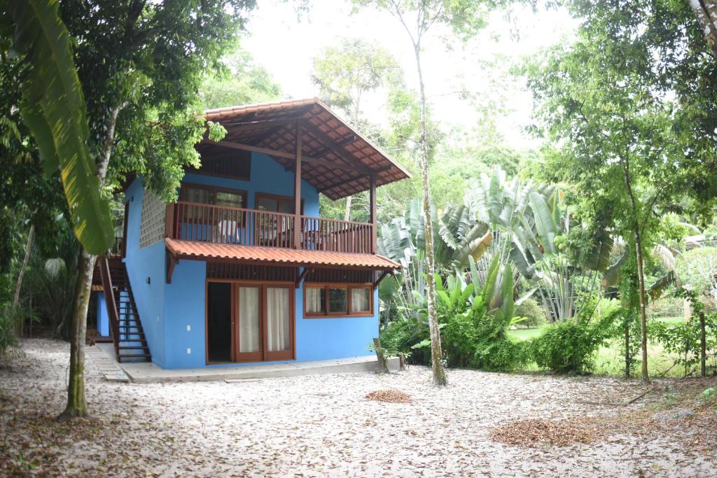 a blue house with a balcony in a forest at Chalés Cumuruxatiba in Cumuruxatiba
