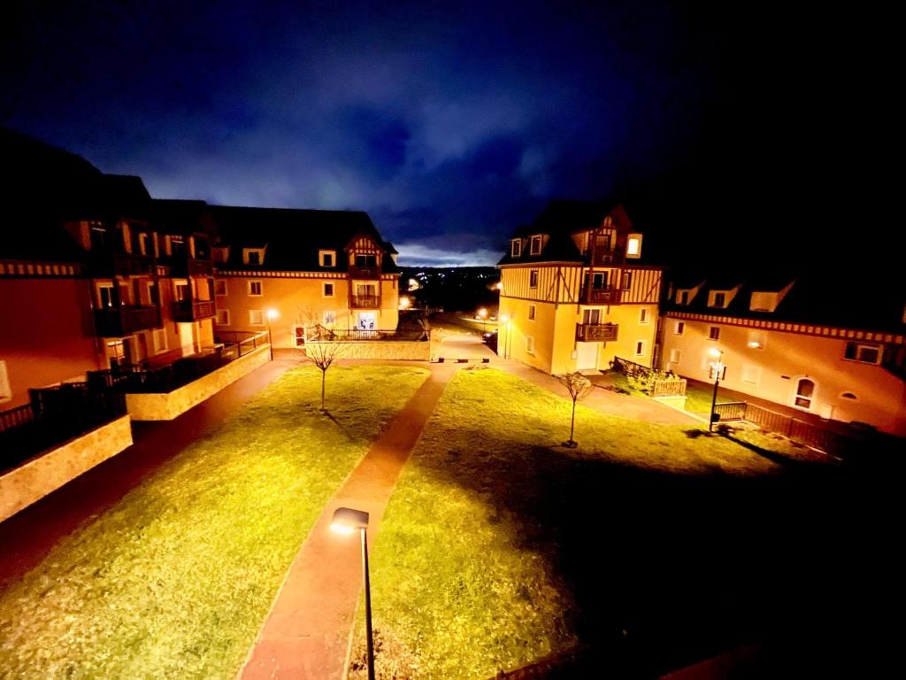 une vue d'une cour avec des bâtiments la nuit dans l'établissement Résidence La Ferme de Deauville - Saint Arnoult, à Saint-Arnoult