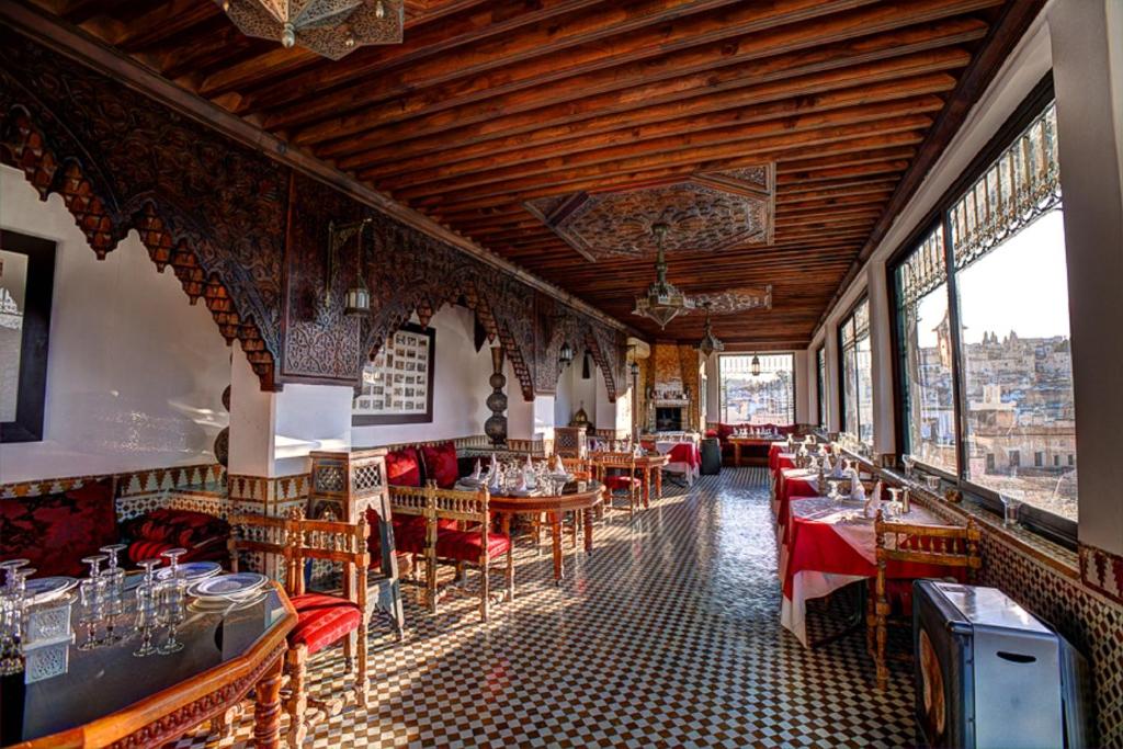a restaurant with tables and chairs in a room with windows at Dar Tazi - Medina View in Fès