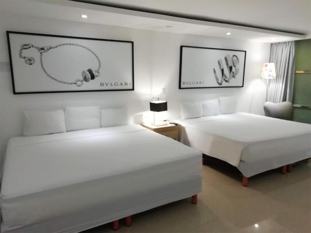 a hotel room with two beds and a chair at Essenzia de Cancun in Canc&uacute;n