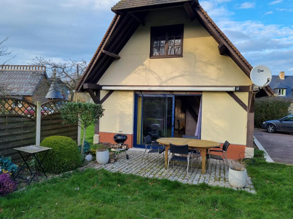 ein Haus mit einem Tisch und Stühlen im Hof in der Unterkunft Gîte côté albâtre in Thérouldeville