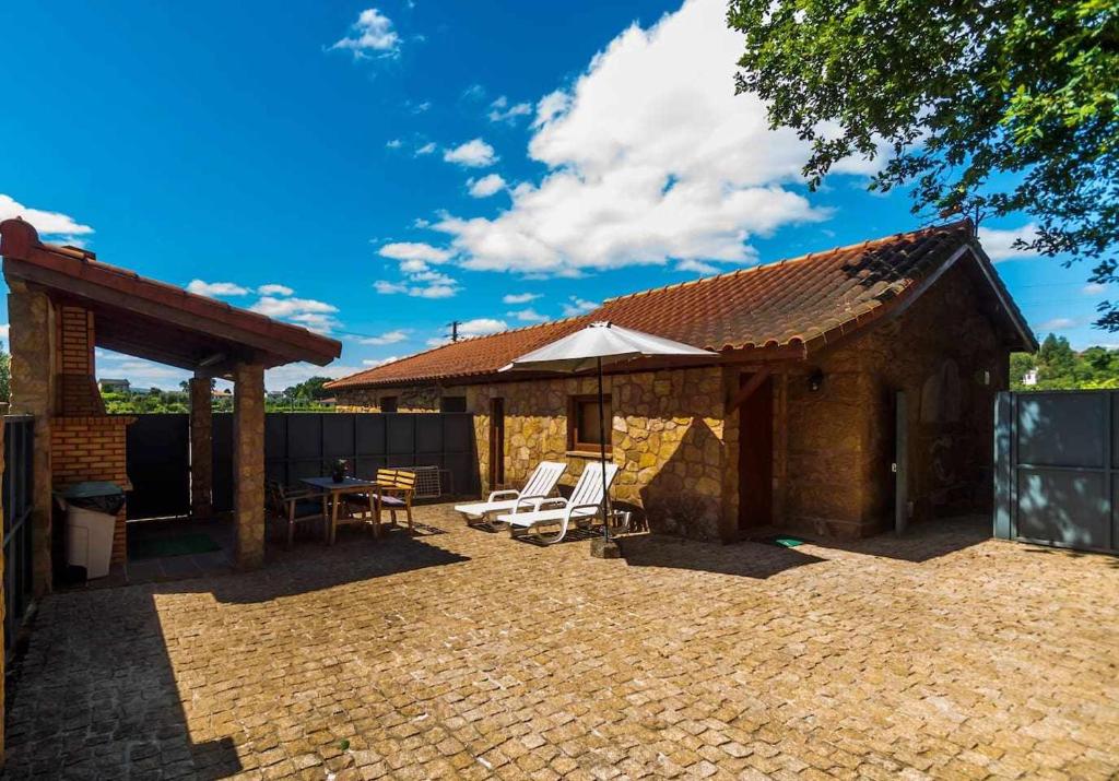 a house with a patio with a table and chairs at Casa das Vinhas Camélias de BastoTurismo Rural in Celorico de Basto