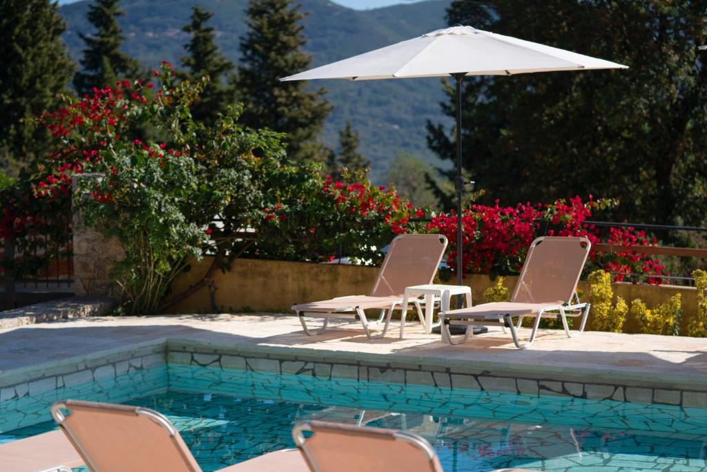 - deux chaises et un parasol à côté de la piscine dans l'établissement Infinity Villa, à Kato Pavliana