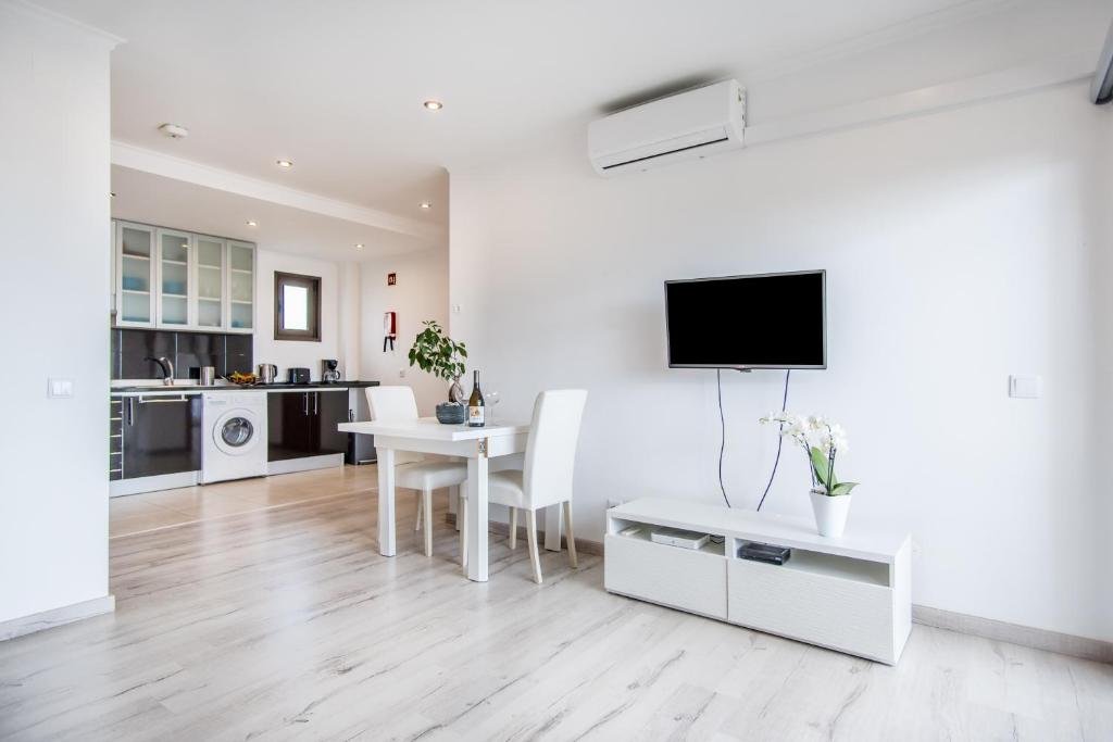 a white living room with a table and a tv at Appartement Chaleureux et Lumineux Proche Mer in Albufeira