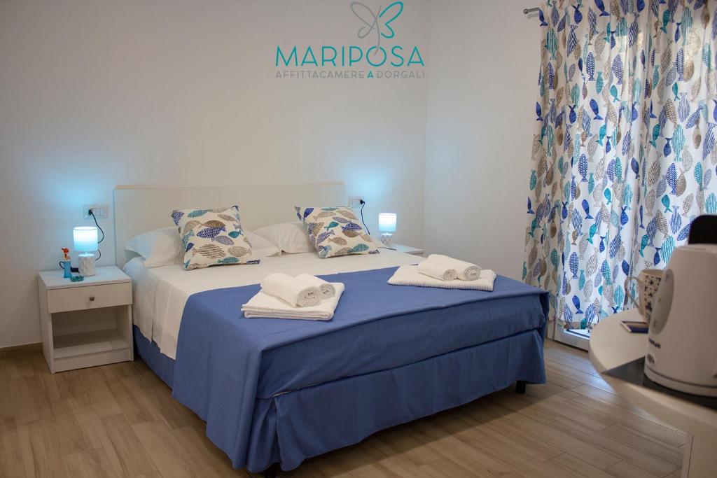 a bedroom with a blue bed with towels on it at Affittacamere Mariposa in Dorgali