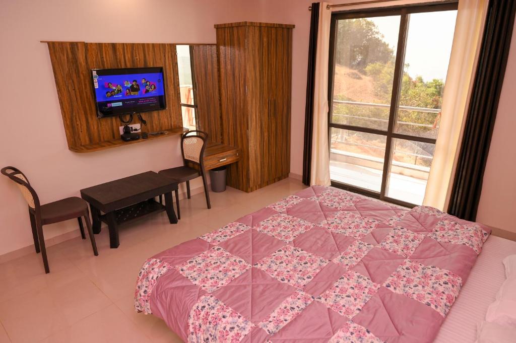 1 dormitorio con 1 cama, TV y ventana en ELITE HOME, en Mahabaleshwar