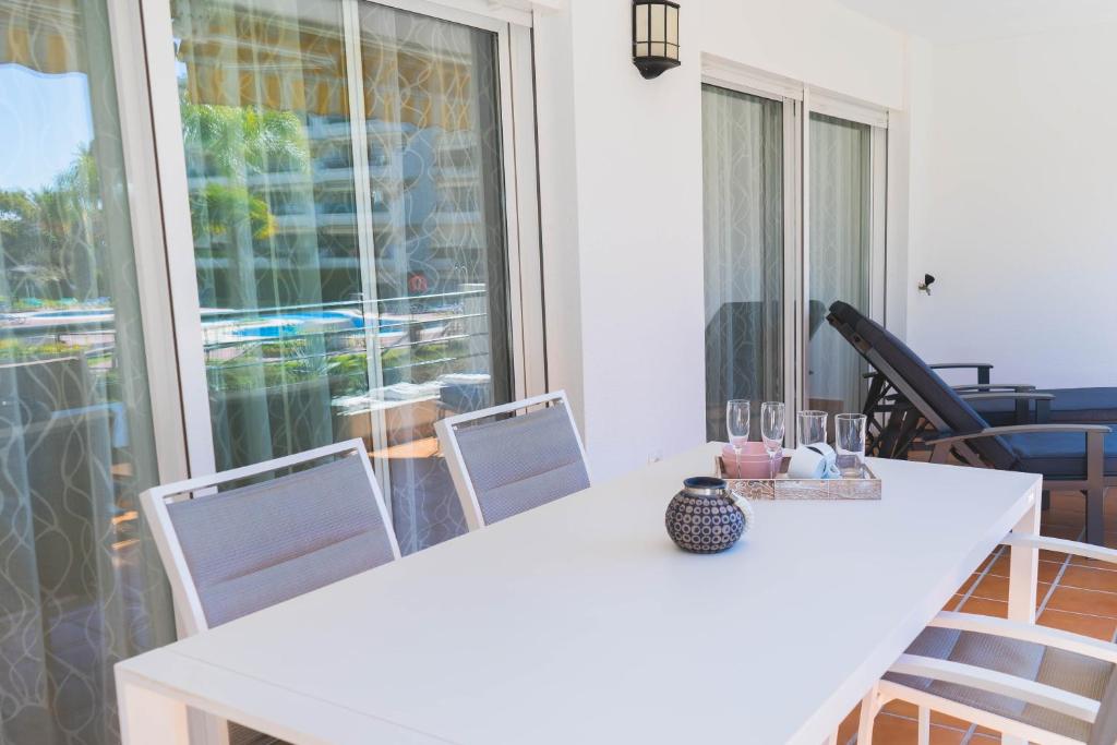 uma mesa branca e cadeiras num quarto com uma janela em Moderno Apartamento en Guadalmina Golf - Marbella em Marbella