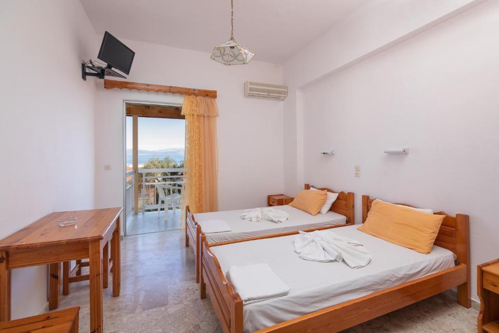 a room with two beds and a table at Corfu Star Apartments in Benitses