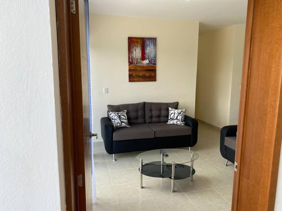 sala de estar con sofá negro y mesa en New Condo in Higuey - Long Term Monthly Stay! en Higuey