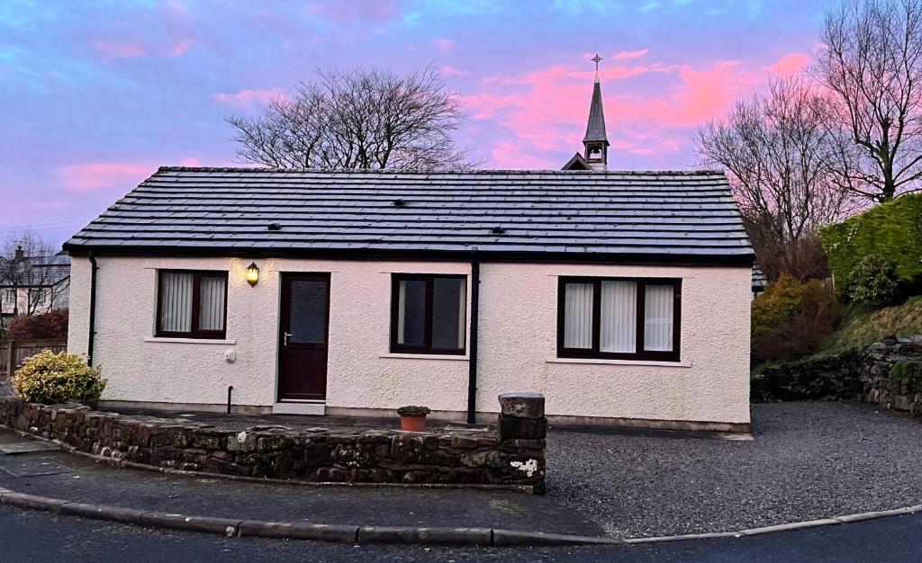 een klein wit huis met een kerktoren op de achtergrond bij Kelton Croft in Kirkland