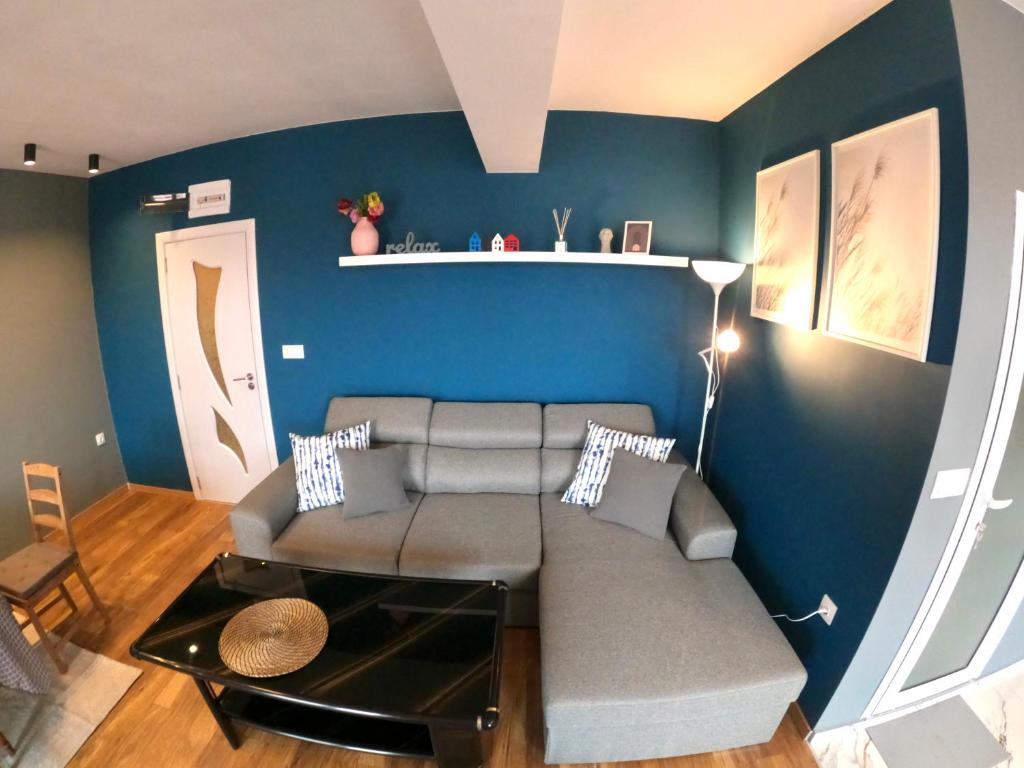 uma sala de estar com um sofá e uma parede azul em Dune Apartment Nessebar em Nessebar