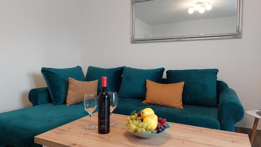 um sofá verde com uma mesa com uma taça de frutas e copos de vinho em Aleksandar em Banja Luka