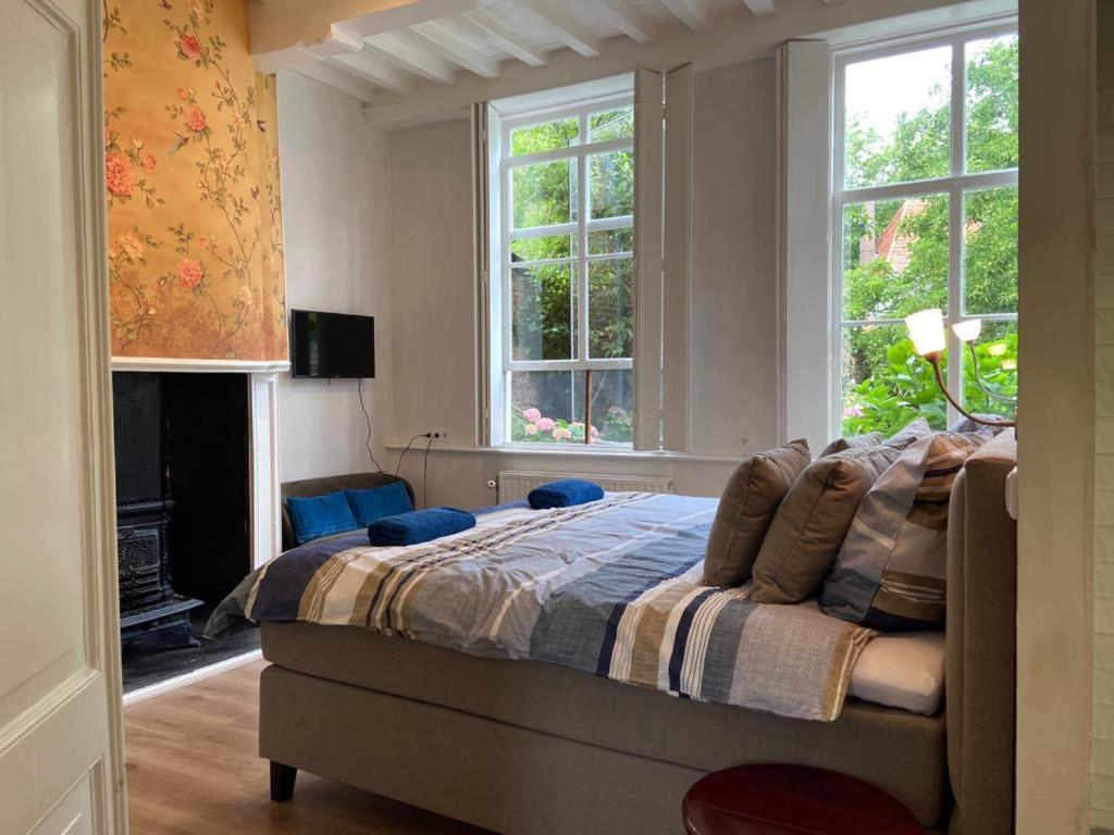 a bedroom with a bed and two windows at Tuinkamer in Monumentaal pand in Veere